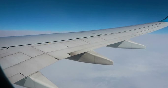 Stunning footage of aerial view above clouds from airplane window with blue sky. view from the airplane window to the blue sky and white clouds. view of the earth from the sky through the clouds.
