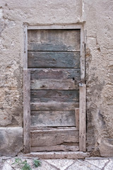 Old closed wooden rectangular door, chain and lock. Stone wall. Italy.