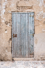 Old closed wooden rectangular door, iron and lock. Stone wall. Italy.