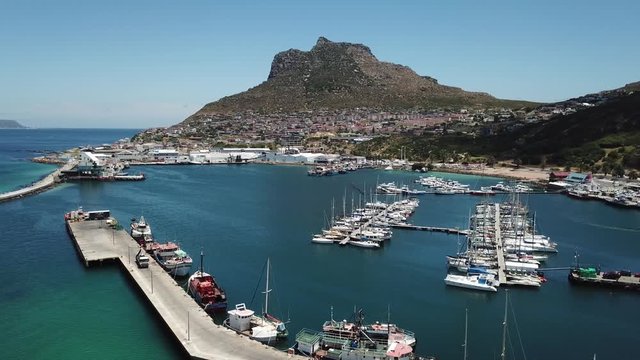 4K summer morning aerial drone video: spectacular Hout Bay harbour, boats, lagoon and beach. Hout Bay is Cape Town fishing harbour and residential suburb in Cape Peninsula, Western Cape, South Africa