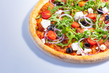 Italian hot pizza with tomato, arugula, cheese Feta, black olives and rings onion isolated on white background