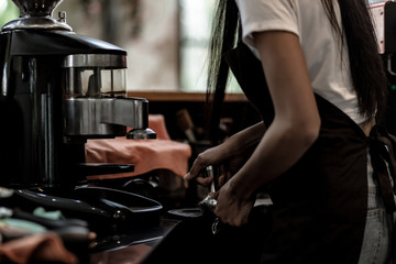 Fototapeta na wymiar Hands of young woman barista woman barista press ground coffee into portafilter to make espresso hot drink. Coffee making cafe barista concept, Small business owner and work concept.