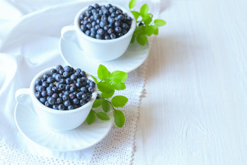 Fototapeta na wymiar ripe blueberries in white cups on a white table. background with blueberries.