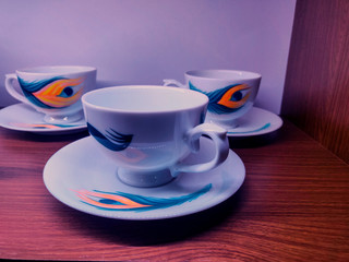 cup and saucer on wooden background with peacock design