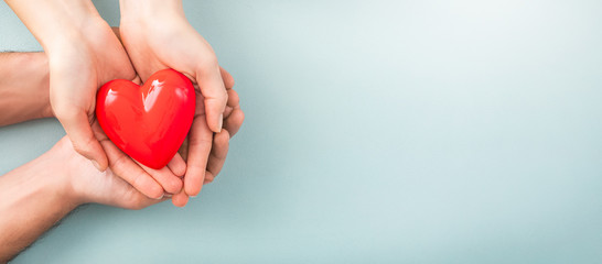 The adult and the child holding red heart.