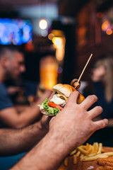 Man holding burger in beer house