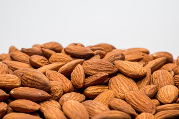 Whole almond nuts on the white background. Healthy vegetarian snack. Close-up photo. Space for your text.
