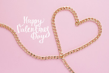 a gold chain laid out in the shape of a heart on a pink background