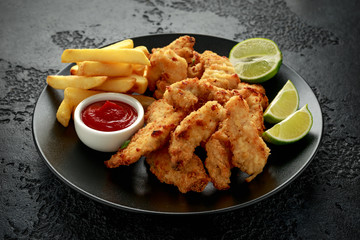 Buttermilk chicken nuggets served on black plate with lime wedges