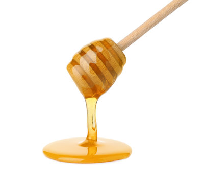 Honey pouring from wooden dipper isolated on white