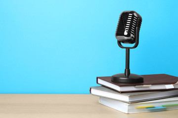 Retro microphone and notebooks on wooden table against light blue background, space for text. Job interview