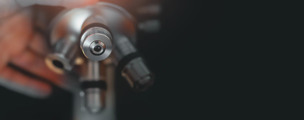 Optical microscope with a human hand. Science study and microscopic observation in laboratory.