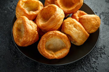 Traditional English Yorkshire pudding side dish on black plate and background