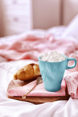 Morning coffee with marshmallow and croissant on bed indoors. Space for text