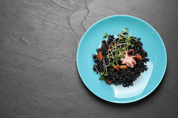 Delicious black risotto with seafood on grey table, top view. Space for text
