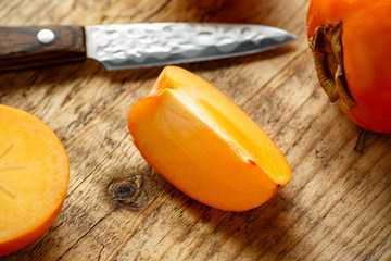 Raw ripe persimmons fruits slices on wooden board