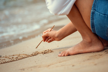 Hands writing on sand and water flow.