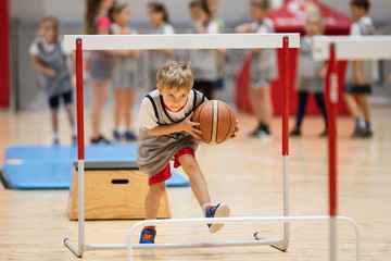 Young boy exercises with a basketball ball in a sports hall