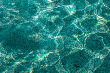 Azure water in the swimming pool. Ripple of water with the reflection of the sun rays.
