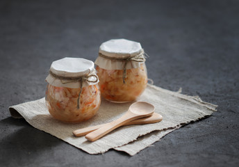 Sauerkraut with carrots and cumin in a jar on a linen napkin with a wooden spoon in a rustic style on a dark background