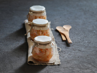 Sauerkraut with carrots and cumin in a jar on a linen napkin with a wooden spoon in a rustic style on a dark background