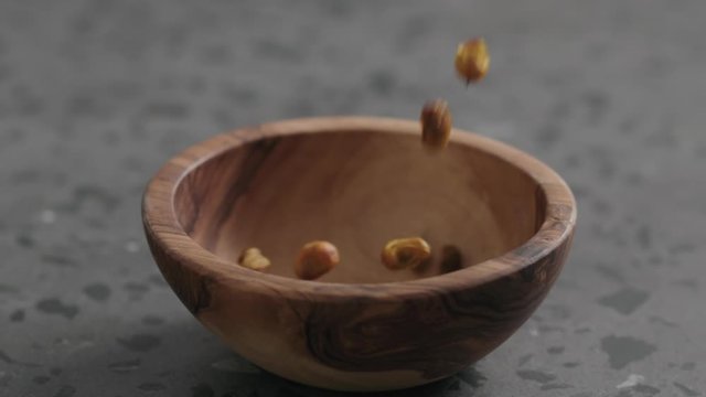 Slow motion dried seaberry falling into olive bowl on terrazzo countertop