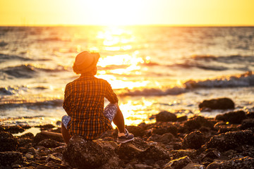A man travel and  sitting on the stone near sea water and sunset in summer.