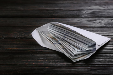 Envelope with dollar bills on black wooden table. Bribe concept