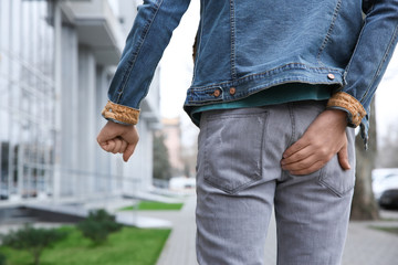 Man suffering from hemorrhoid pain outdoors, back view