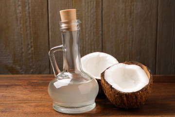 Fototapeta na wymiar Coconut oil in glass jug on wooden table