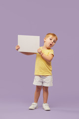Little child boy holding a white banner on purple background. Funny Face. Copy space for text