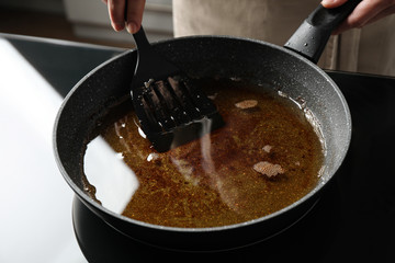 Woman holding frying pan with used cooking oil, closeup