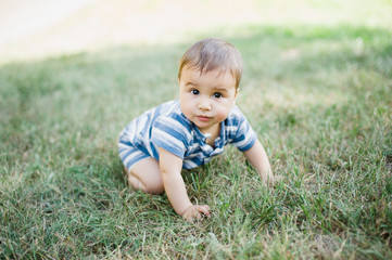 Naklejka na ściany i meble 7 month child crawls on grass in yard,