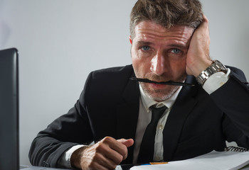 corporate business work stress - young desperate and frustrated businessman working stressed and overwhelmed at office computer desk biting pen feeling exhausted