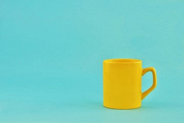 Yellow bright ceramic mug on a light blue background