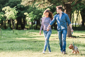 Lifestyle, happy couple of two walk on a sunny day in the park with a dog