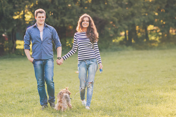 Lifestyle, happy couple of two walk on a sunny day in the park with a dog