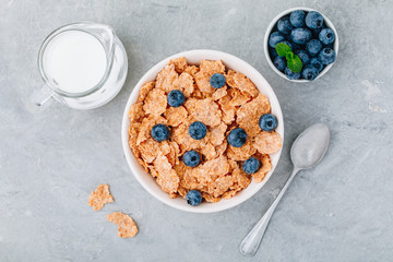 Whole grain breakfast cereal flakes with fresh blueberries and milk. Top view, copy space