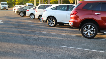 Closeup of rear, back side of red car with  other cars parking in outdoor parking area with natural background in bright sunny day. 