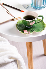 a cup of herbal tea on a table with notepad and candle . Bedroom interior