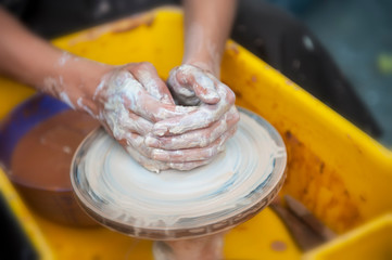 The potter makes pottery dishes on potter's wheel.