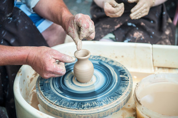 The potter makes pottery dishes on potter's wheel.