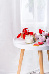 Homemade Valentines day heart cookies, pink roses and candle on white table over window, copy space