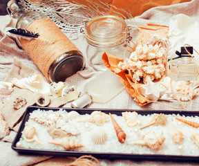 a lot of sea theme in mess like shells, candles, perfume, girl stuff on linen, pretty textured post card view vintage close up