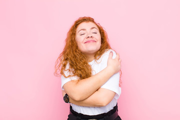 young red head woman feeling in love, smiling, cuddling and hugging self, staying single, being...