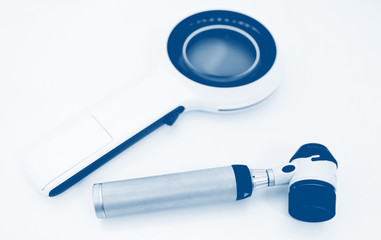 Dermatoscope and electronic magnifying glass close-up on a white background. Prevention of melanoma