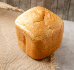 Wheat bread, white. On the table lies a loaf of white bread, slices of bread. Close-up.