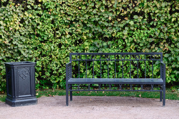 Park bench, white bench, black cast-iron bench. Handbag on the bench.