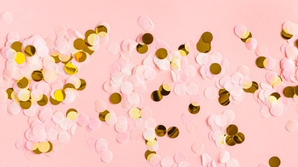 Gold and light pink confetti on a pink background, copy space. Soft festive background with confetti. Valentine's day, birthday or wedding background.