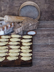 On the kitchen cutting board, ready-made dumplings with ingredients for making dough and various kitchen utensils.